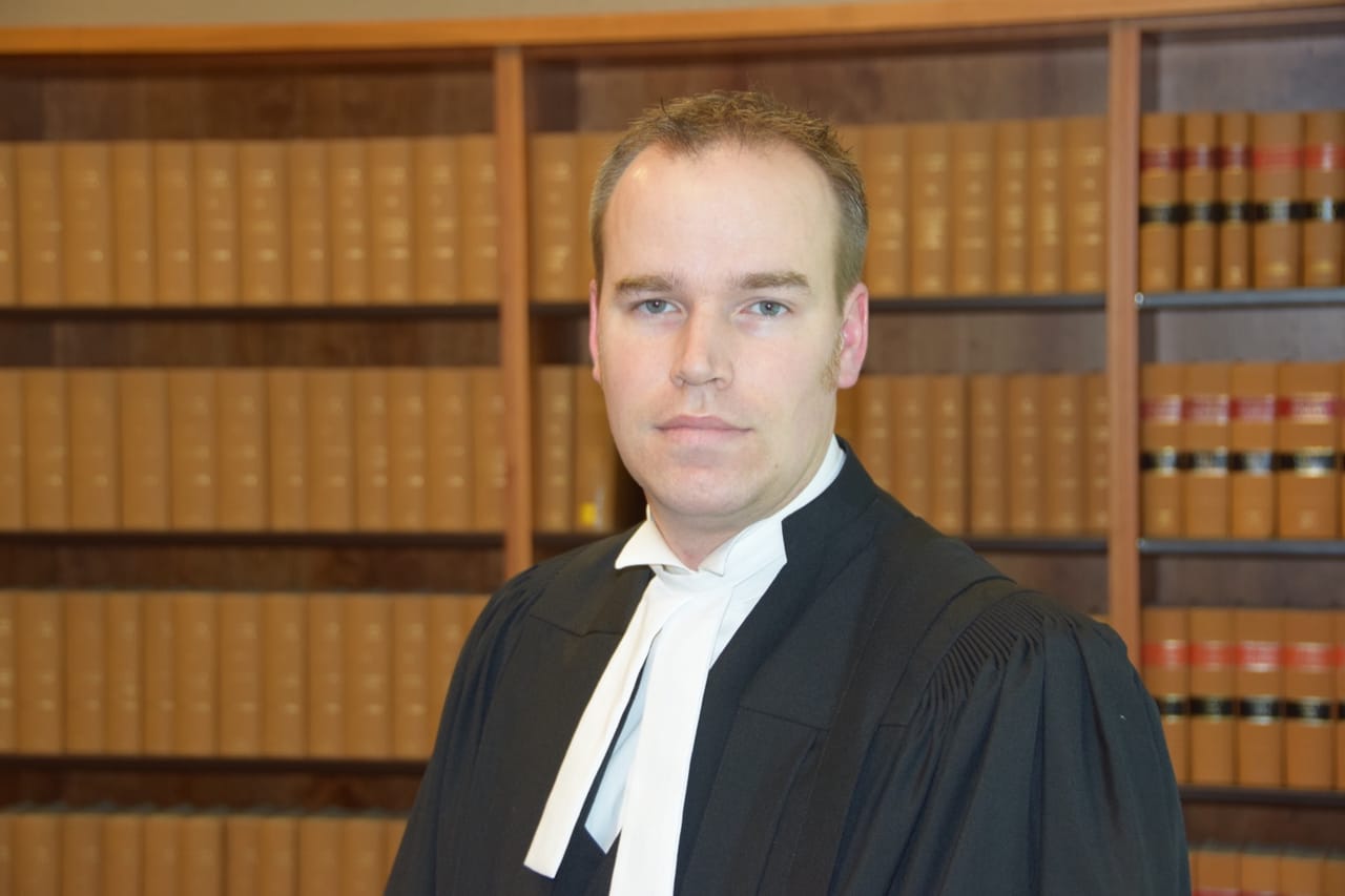 Robin Anderson in barrister's robes in front of a wall of law reports