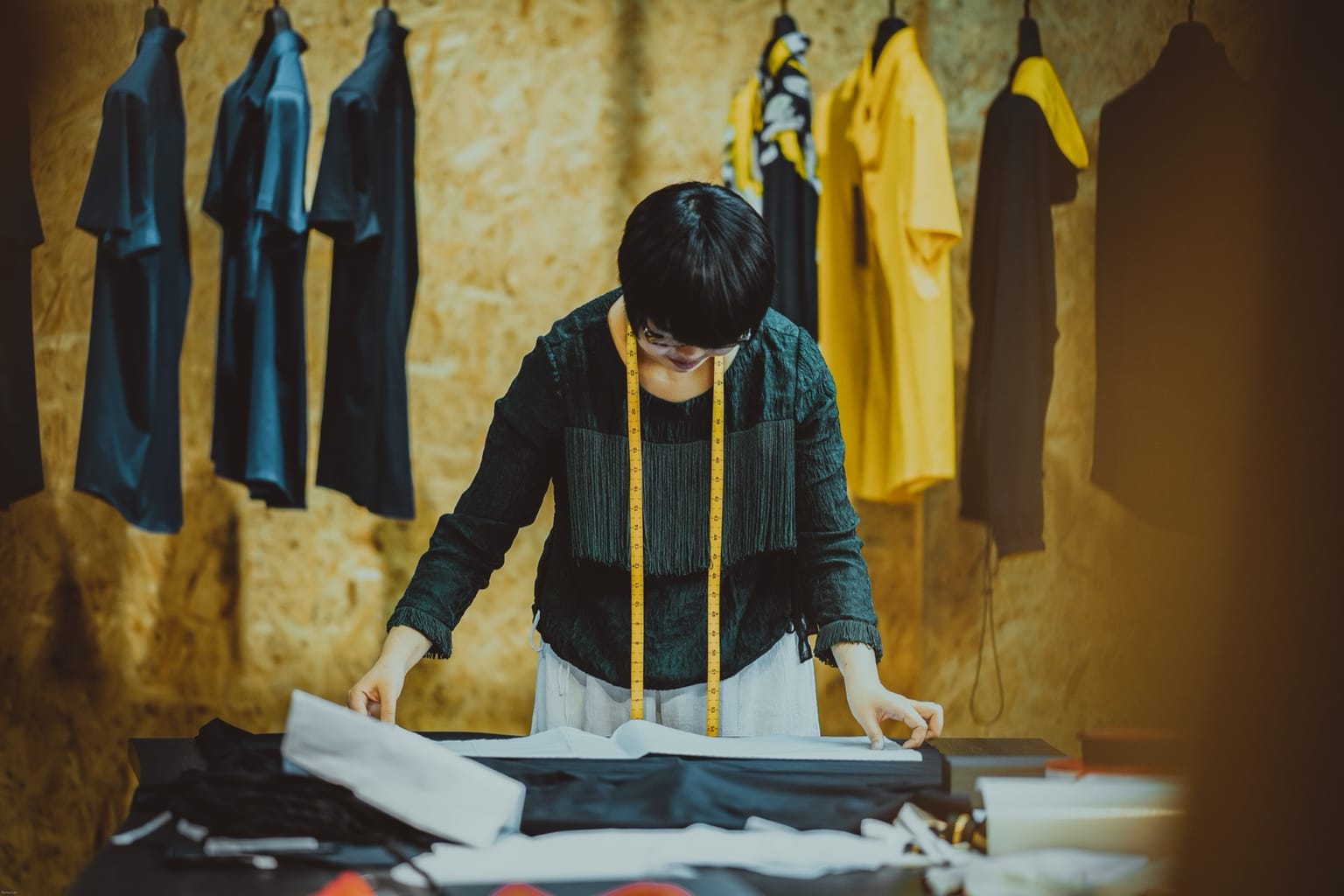 Tailor working at a bench surrounded by garments